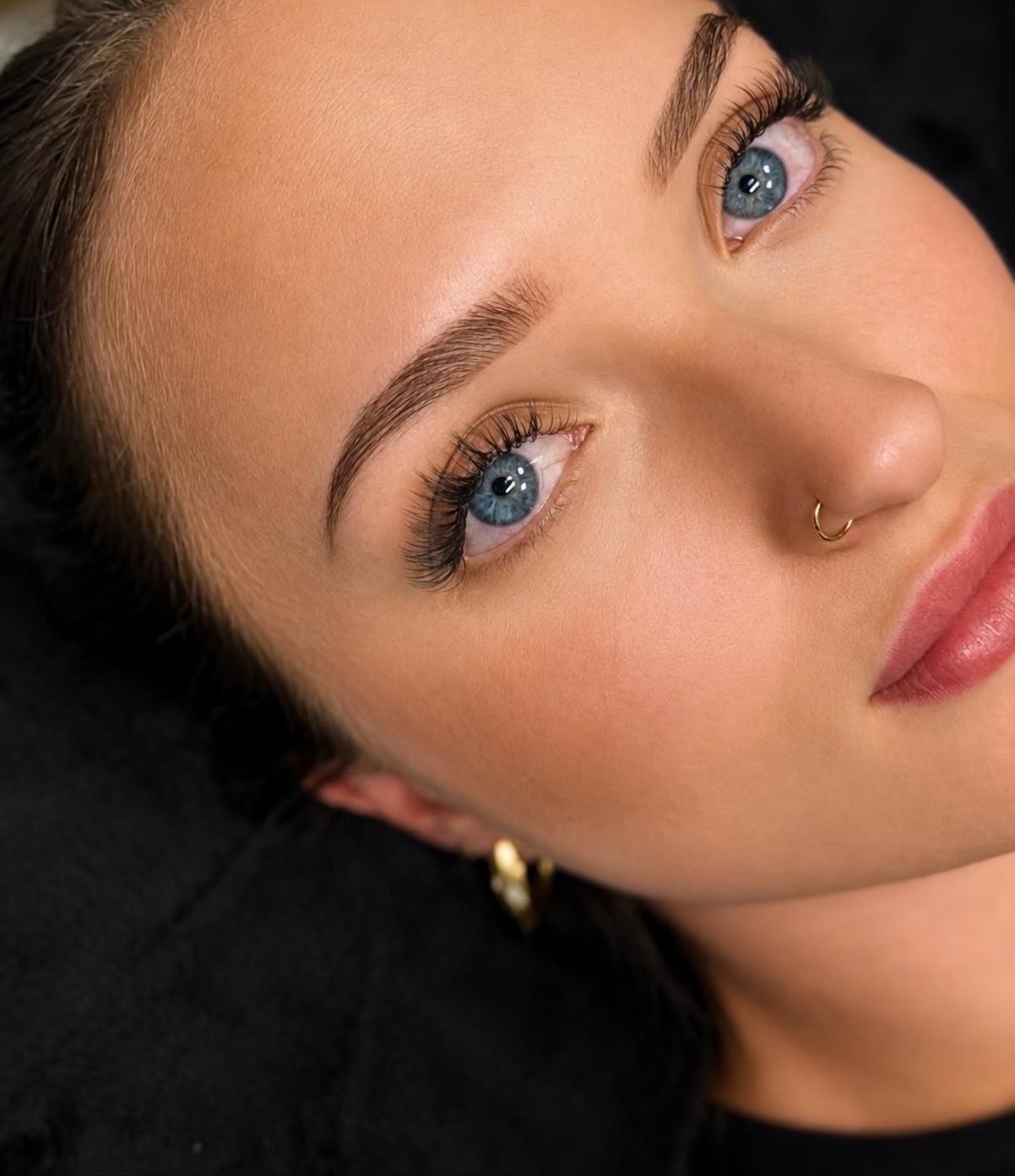 Nahaufnahme eines Auges mit natürlich wirkender Wimpernverlängerung und gestylter Augenbraue
